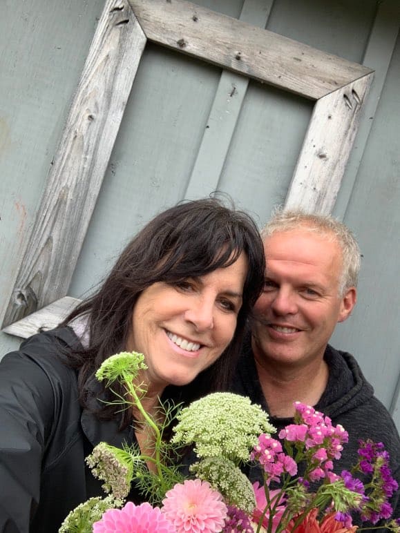 a man and woman smiling and holding flowers