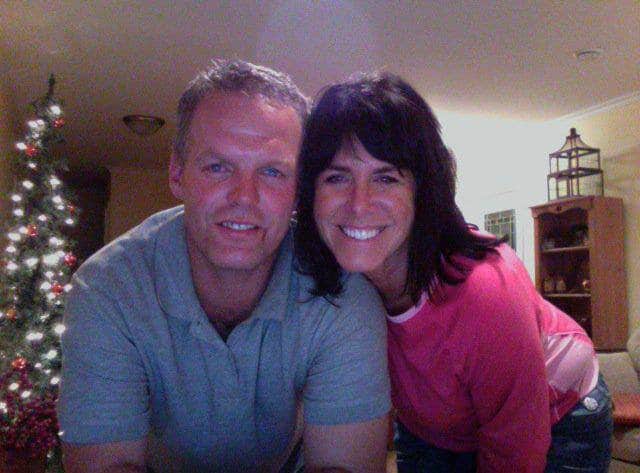 a man and woman smiling and a Christmas tree in the background