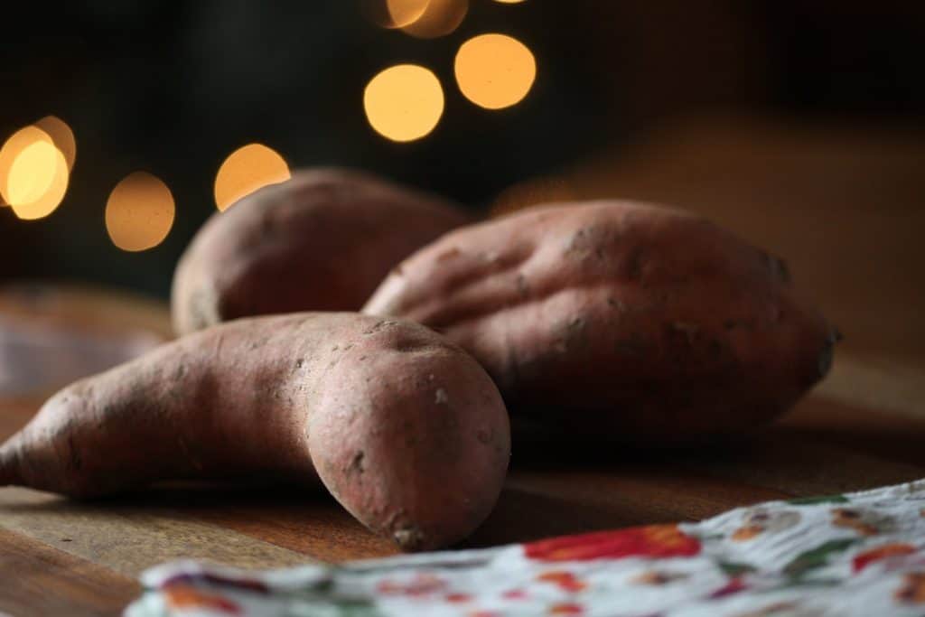 sweet potatoes, sitting on a brown butcher block with twinkling lights in the background
