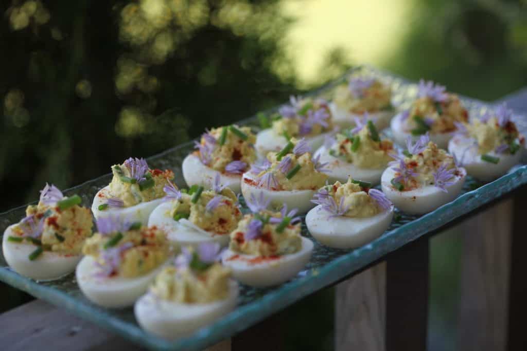 deviled eggs on a glass plate, showing how to use fresh chives from the garden