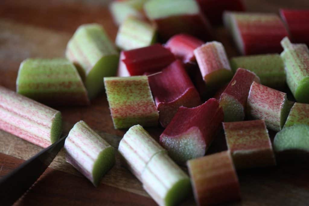 rhubarb being chopped on a cutting board with a knife
