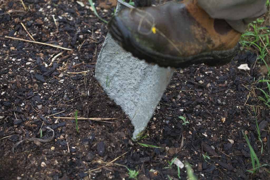 a boot digging a hole with a shovel in brown soil