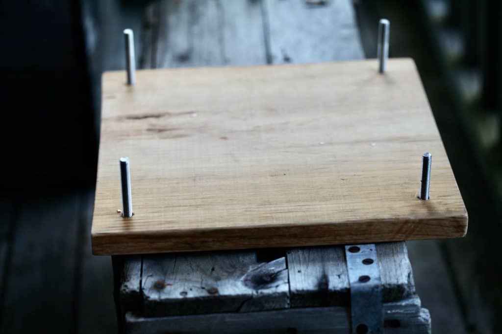 a piece of wood with bolts in four corners