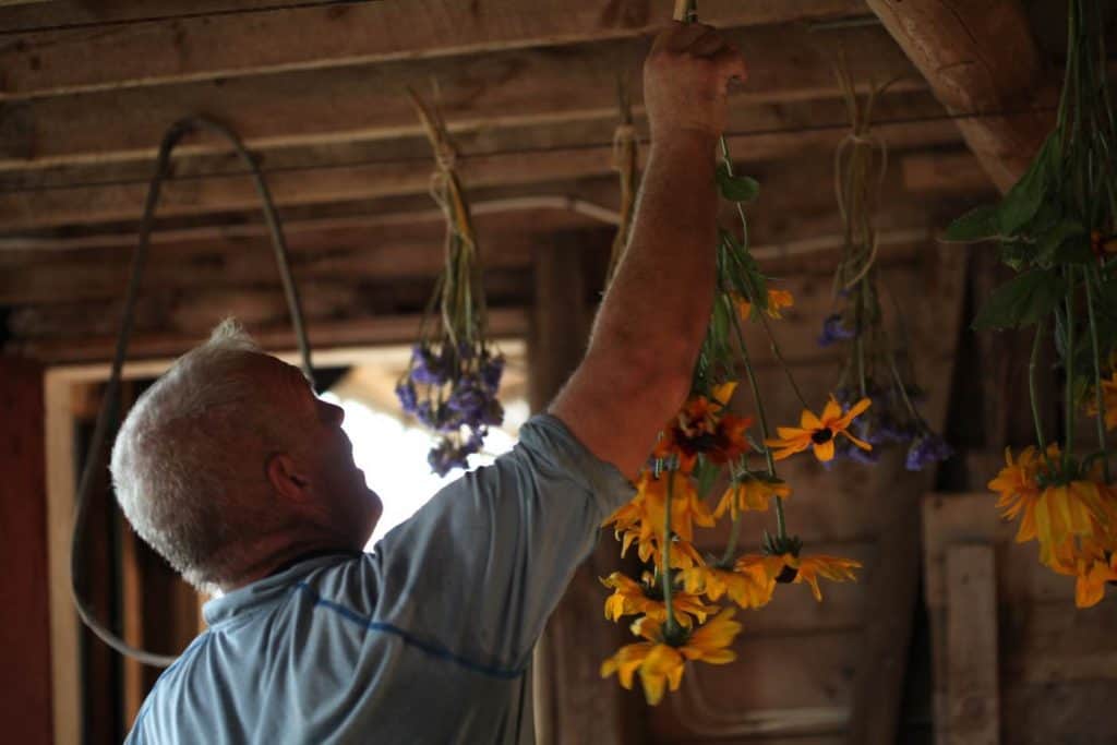 a man hanging flowers to dry