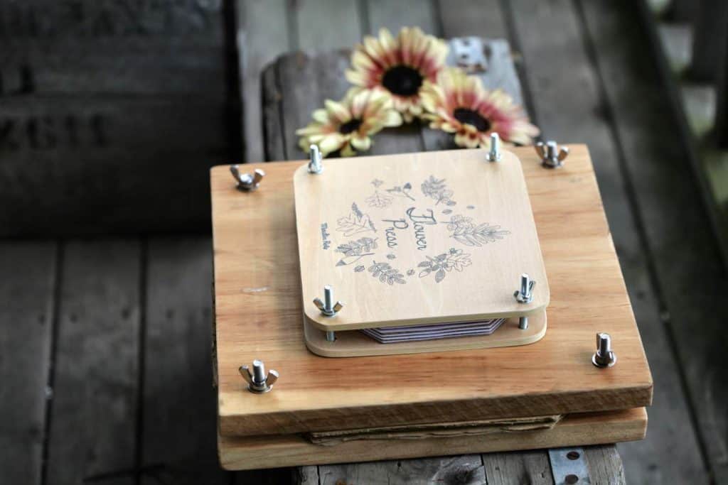 two flower presses next to sunflowers on a grey wooden crate