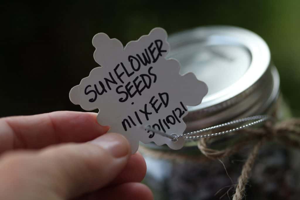 a hand holding a label demonstrating to label and date seeds that have been stored
