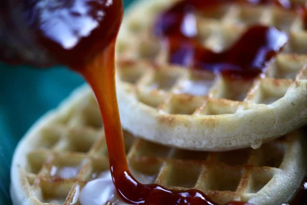 drizzling apple cider syrup over waffles