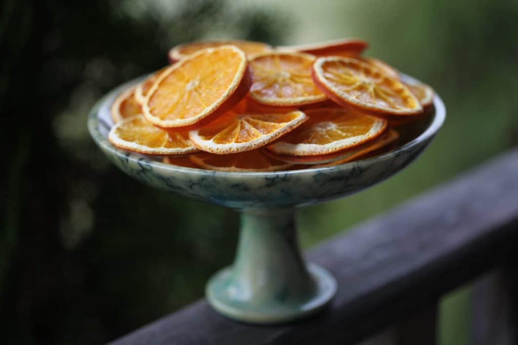 dried orange slices on a green alabaster platter on a wooden railing