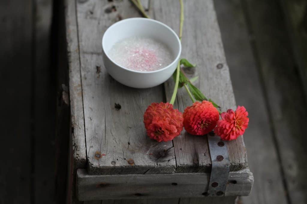 zinnias and a bowl containing silica beads on a wooden crate