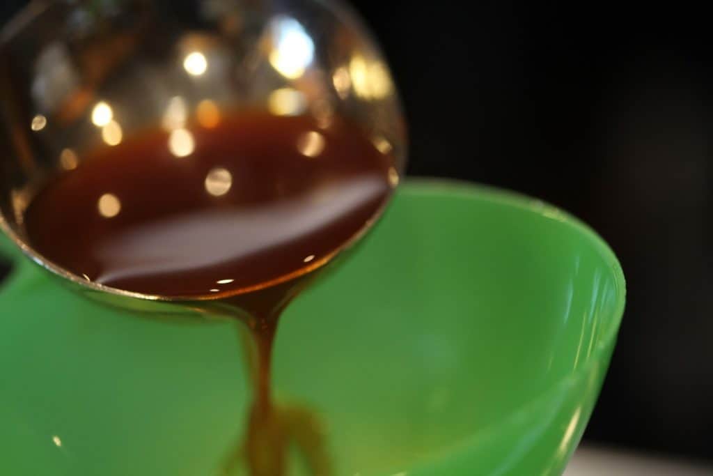 apple cider syrup being poured into a green funnel