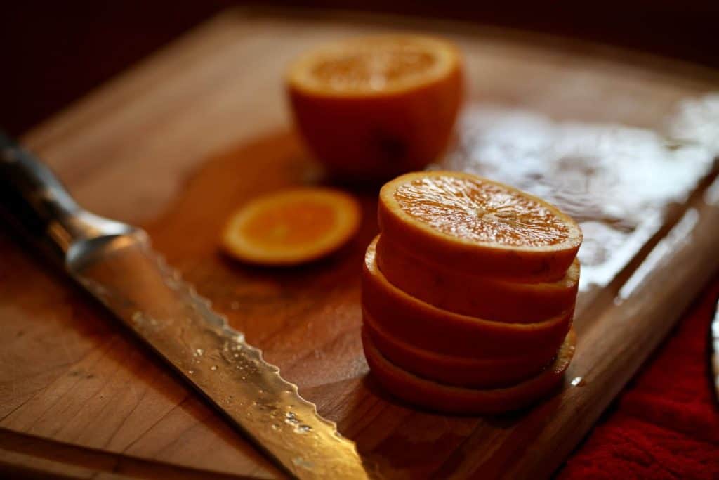 sliced oranges and a knife on a cutting board