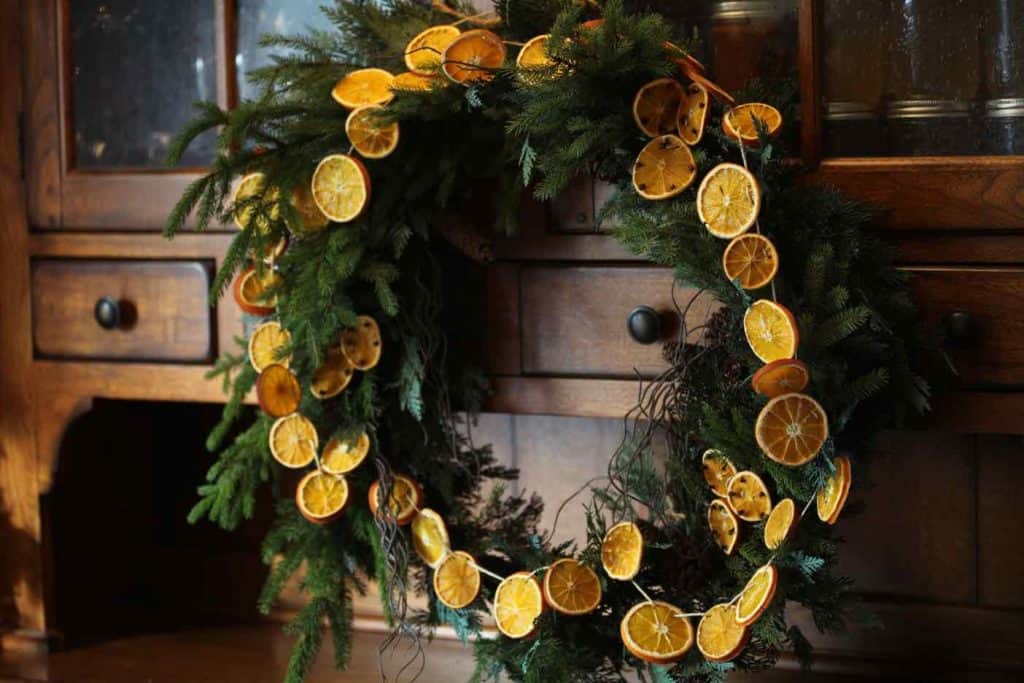 an evergreen wreath garnished with a garland of dried orange slices