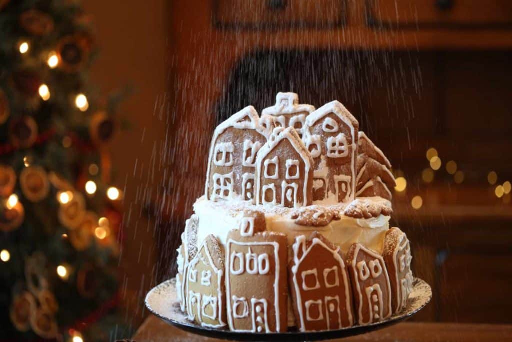 decorating the gingerbread cake with icing sugar snow