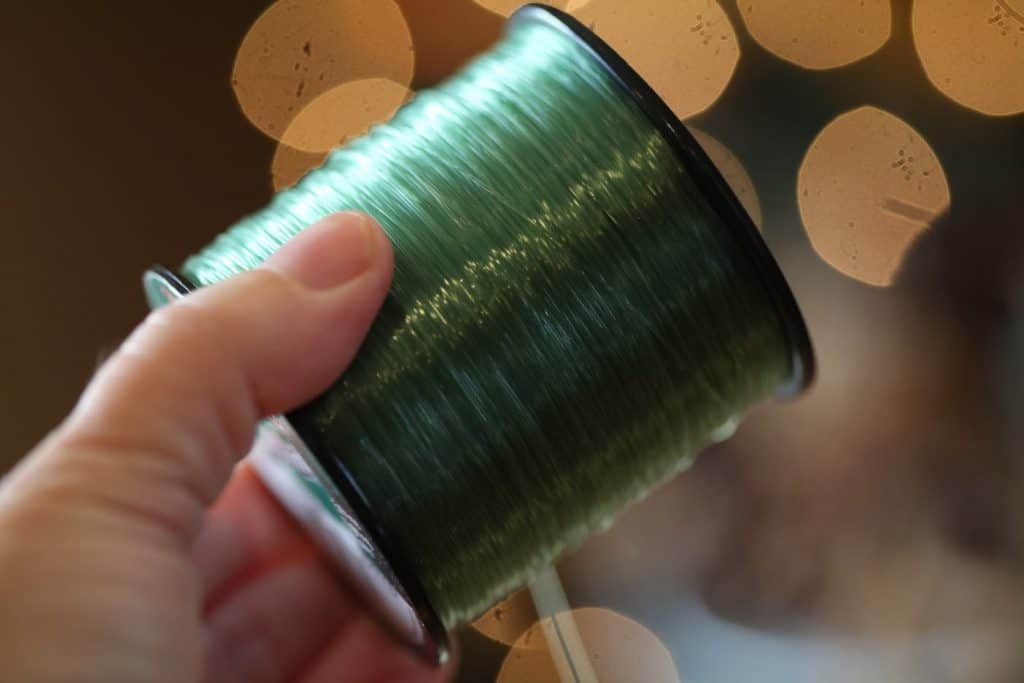 a hand holding green fishing twine for garland