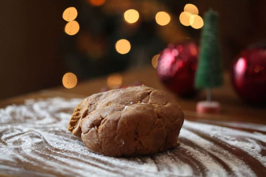 a ball of brown gingerbread dough on a flat floured surface