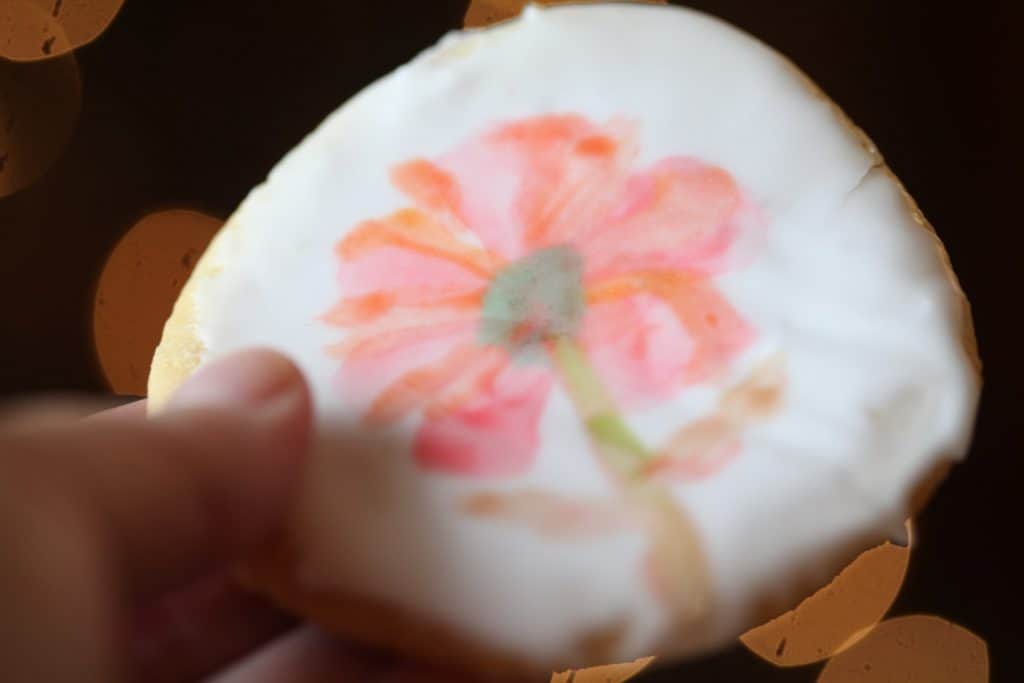 a hand holding a watercolor sugar cookie