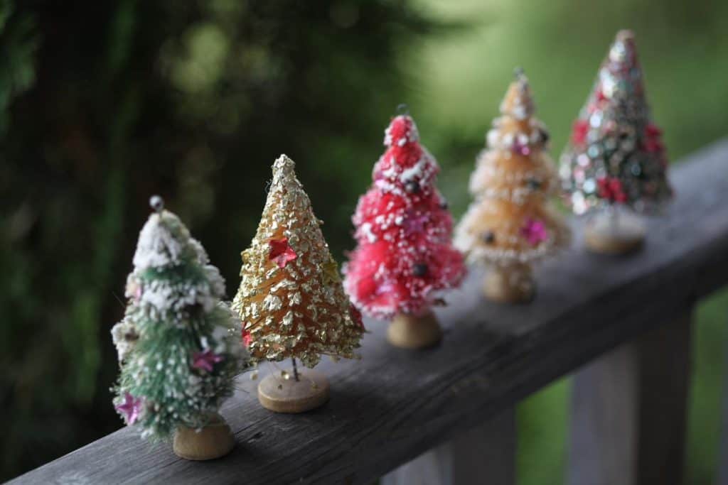 little mini vintage bottle brush Christmas trees on a wooden railing