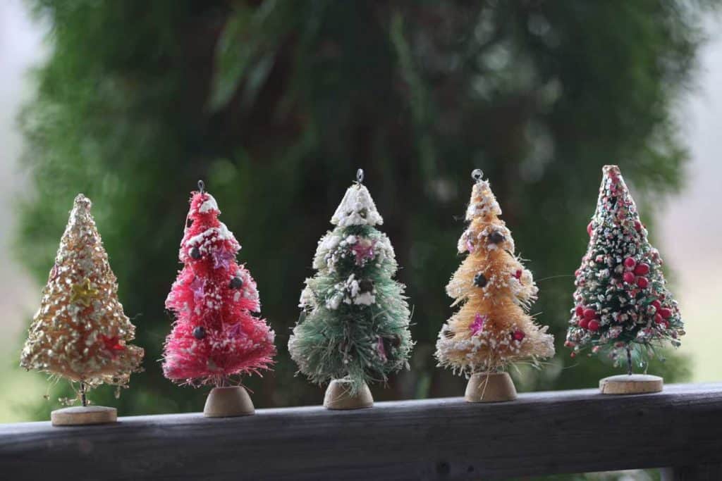 little mini vintage bottle brush Christmas trees on a wooden railing