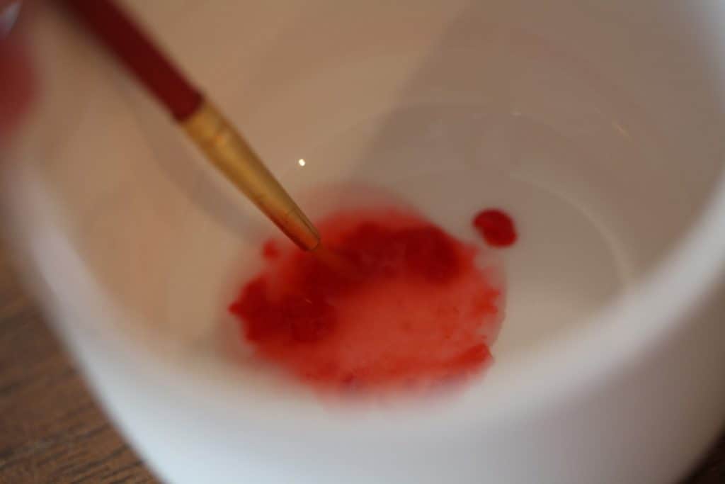 a paintbrush mixing red edible paint