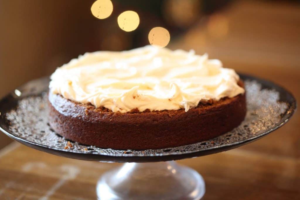  a single layer of gingerbread cake with cream cheese icing on a cake platter