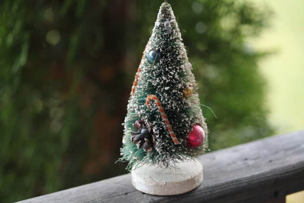 vintage bottle brush Christmas tree,  on a wooden railing