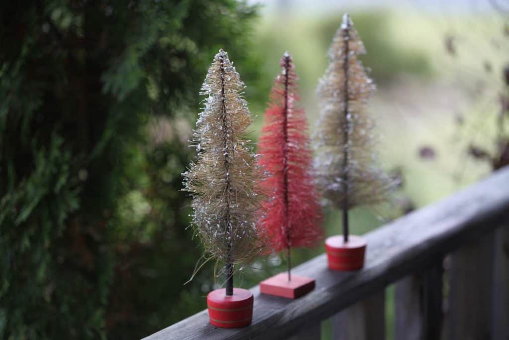 vintage bottle brush Christmas trees on a wooden railing