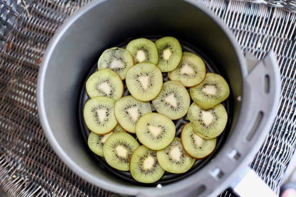 kiwi slices in the air fryer basket ready for dehydrating