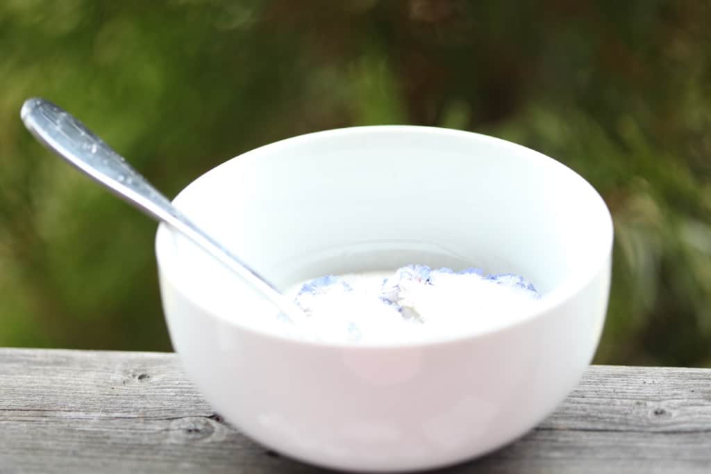 drying flowers in silica gel in a white bowl with a spoon