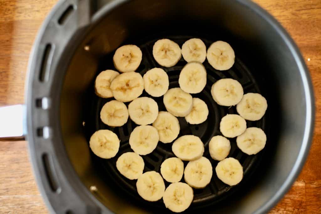 banana slices in an air fryer basket for dehydrating