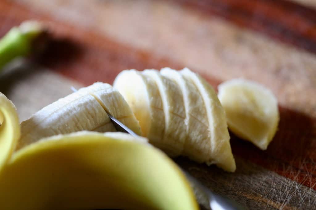 a knife cutting a banana into even sized slices