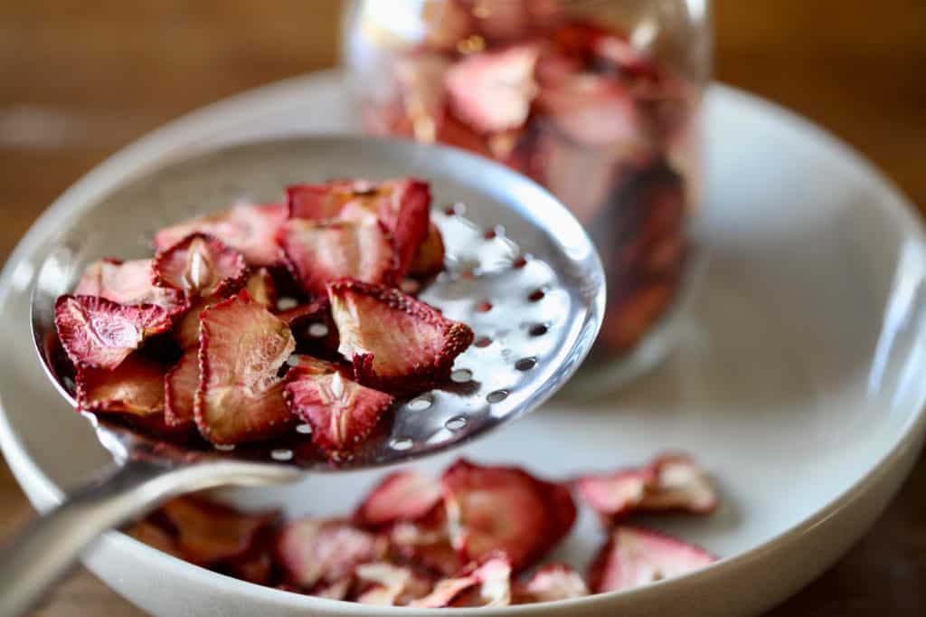 dehydrated strawberries in a bowl and spoon, as well as a mason jar