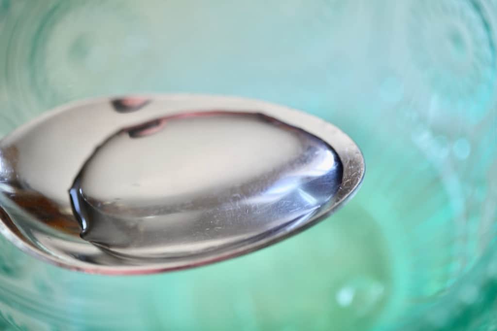a spoonful of water over a green bowl