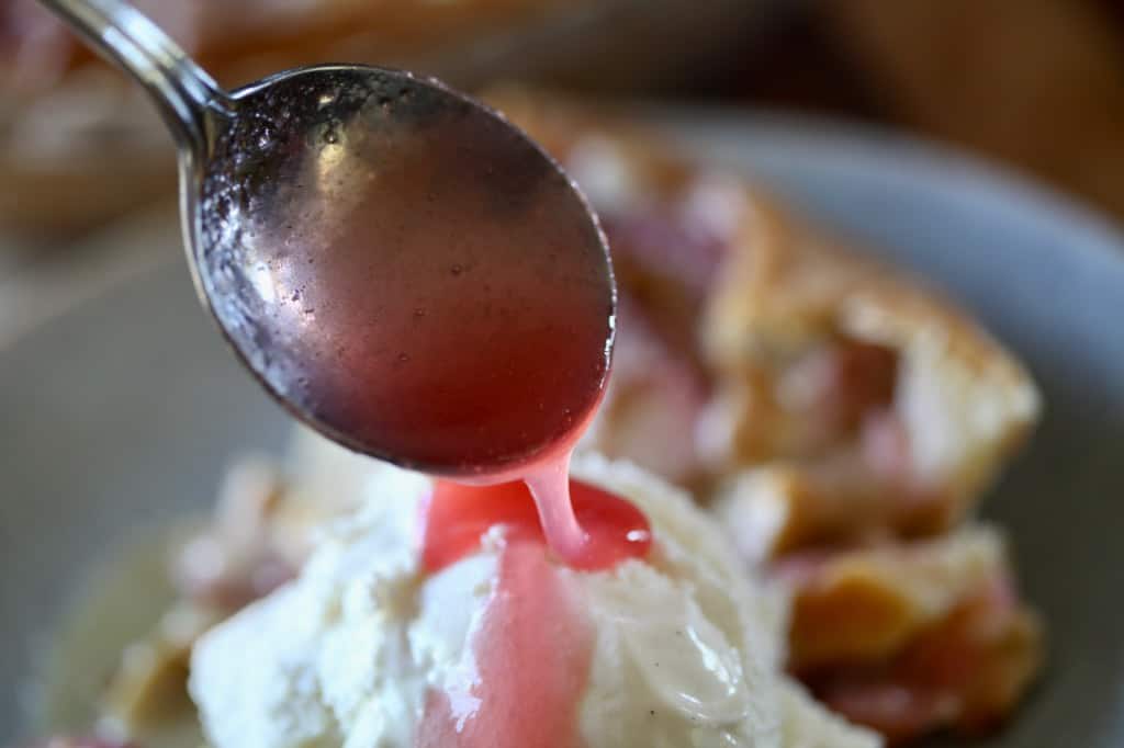 drizzling rhubarb syrup over rhubarb custard pie and ice cream