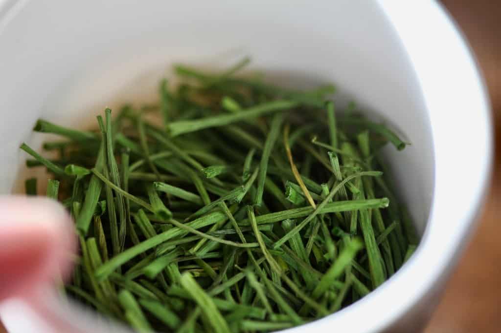 a small white bowl full of chives dried in the air fryer