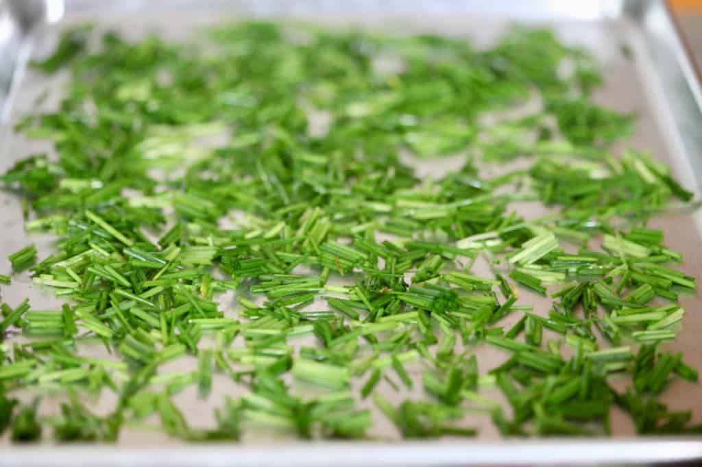 chives spread out on a baking sheet in a single layer to freeze