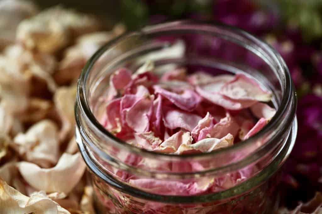dried pink rose petals in an open mason jar