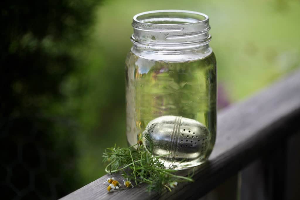 a cup of steeping chamomile tea on a wooden railing