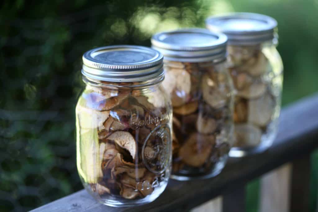 dried pears in mason jars on a wooden railing