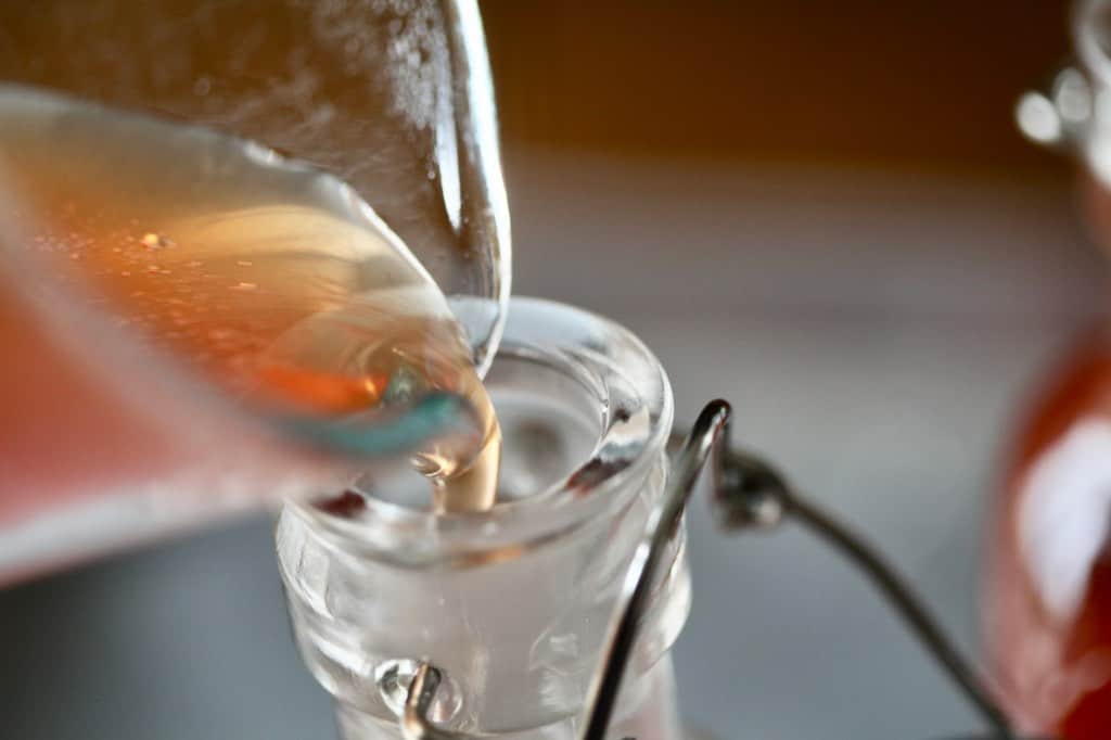 pouring the rose hip syrup into sterilized containers when the cooking time is completed