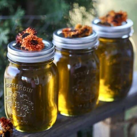calendula oil in mason jars topped with dried calendula flowers