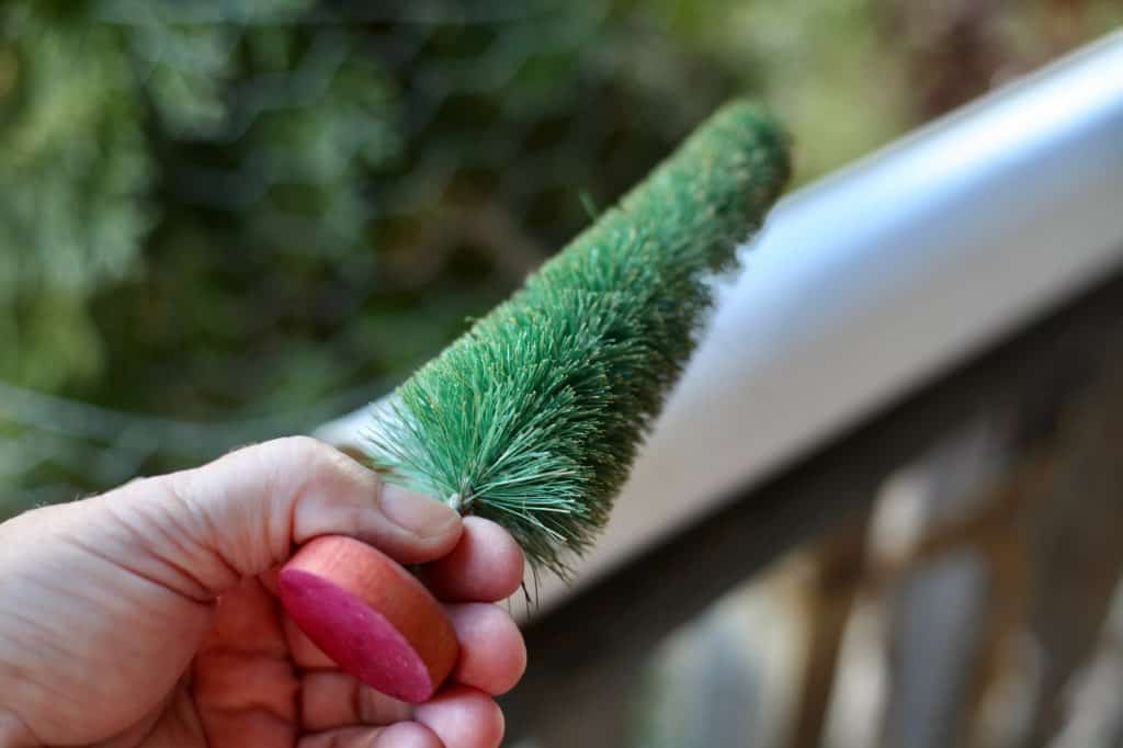 a hand holding up a green bottle brush tree