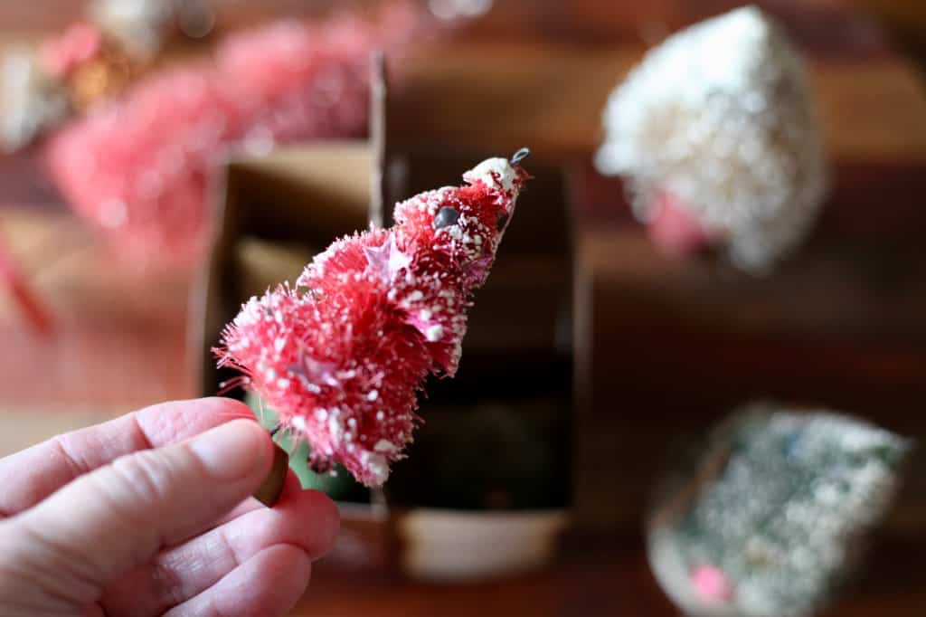 a hand holding up a red vintage bottle brush tree to store