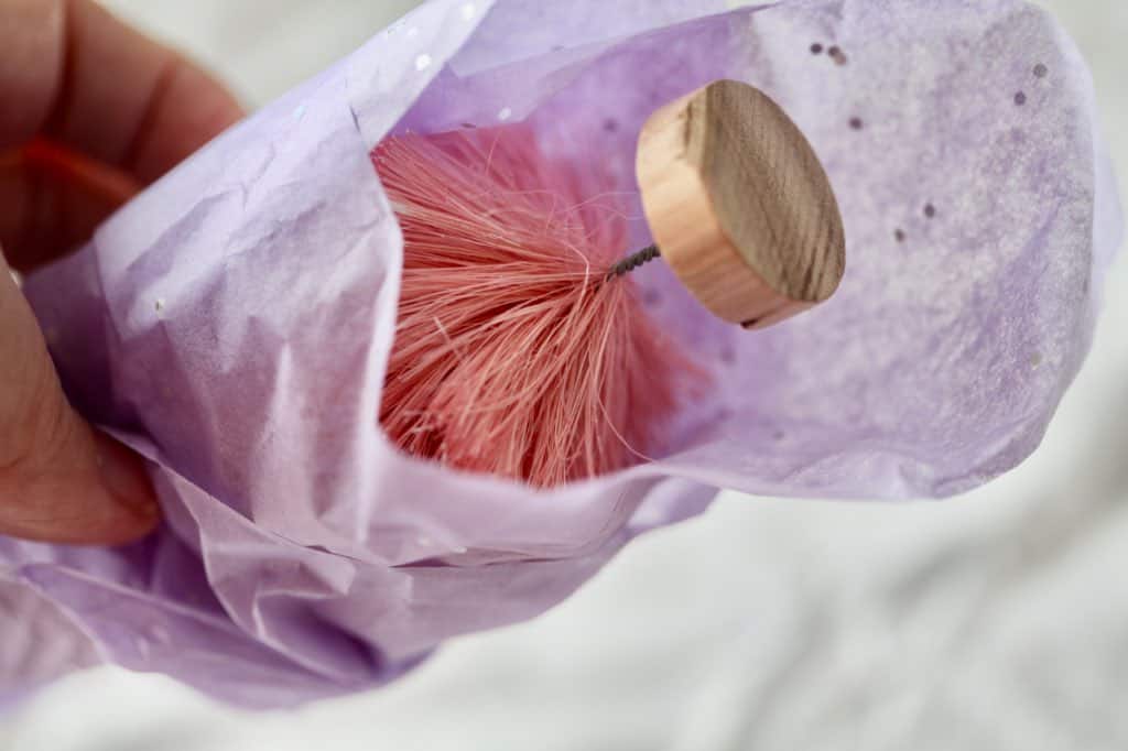 a pink bottle brush tree in wrapped in purple tissue paper