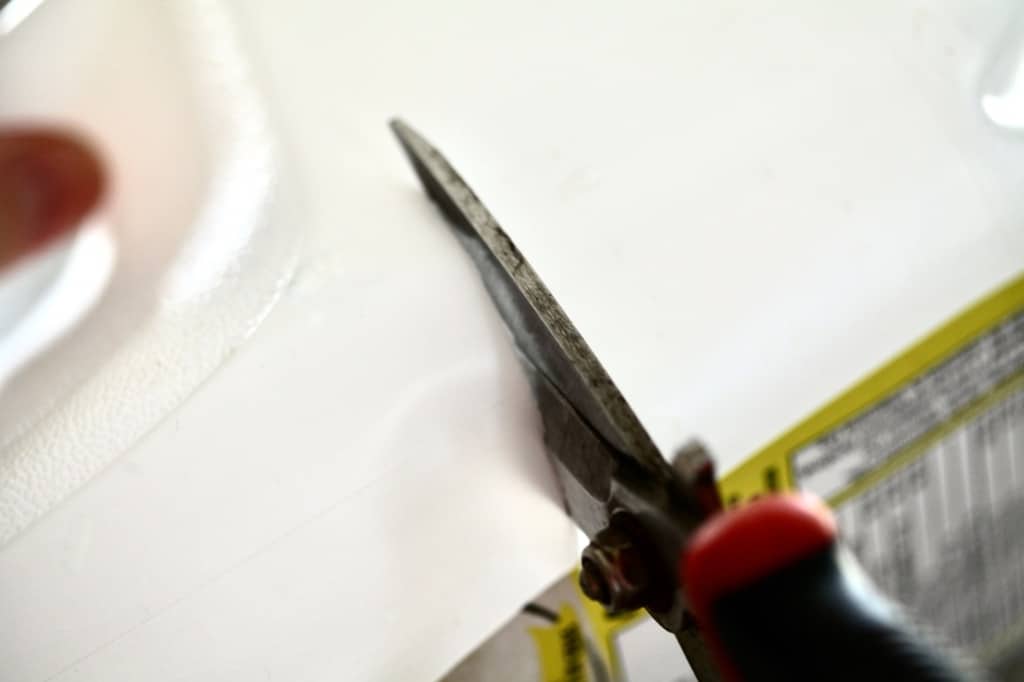 garden shears cutting a white milk jug to prepare for winter sowing