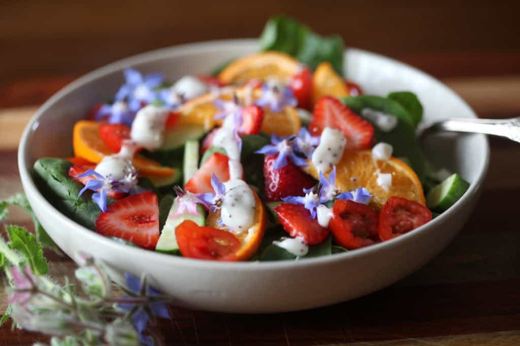 a brightly colored salad garnished with edible flowers