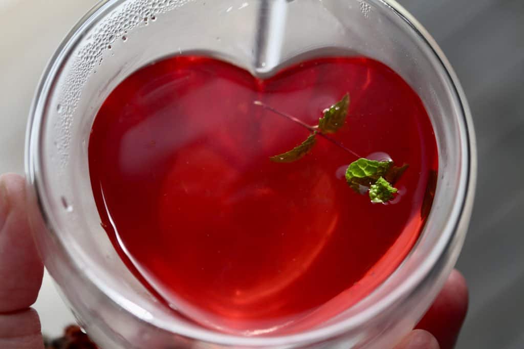 a cup of sumac tea in a heart shaped glass cup