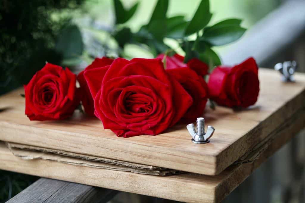 a wooden flower press with red roses sitting on top