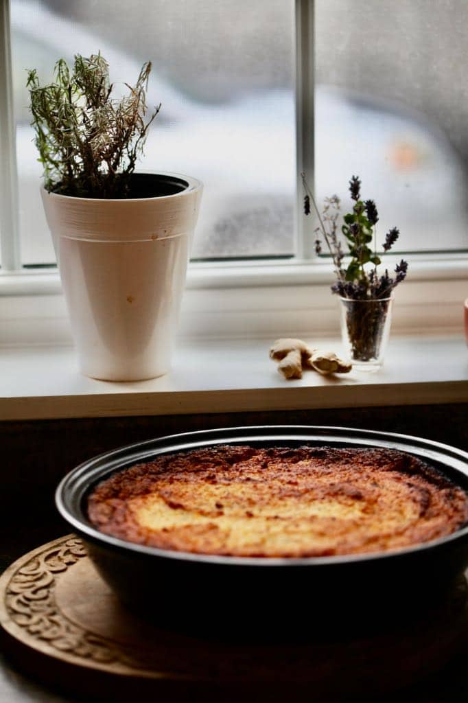 cassava pie on a cutting board next to a window ledge with plants